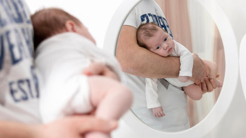 A baby being carried by its father to keep colic symptoms at bay