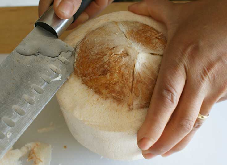Inserting knife into edge of coconut