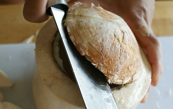 Using flat of knife to lever up coconut dome