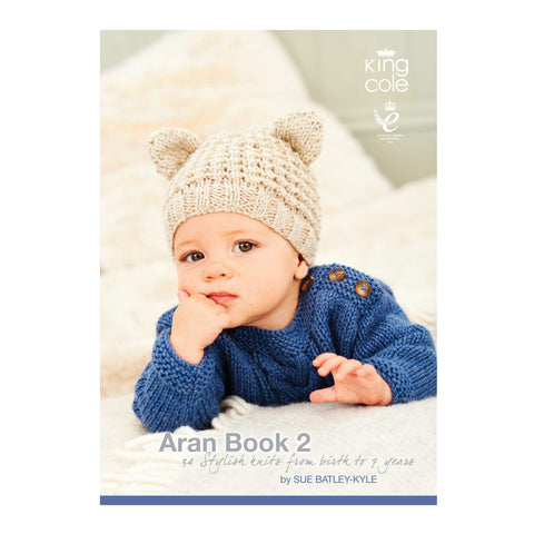 Image of King Cole Aran Book 2 knitting pattern book featuring a young child wearing a hand-knitted Aran hat with ears