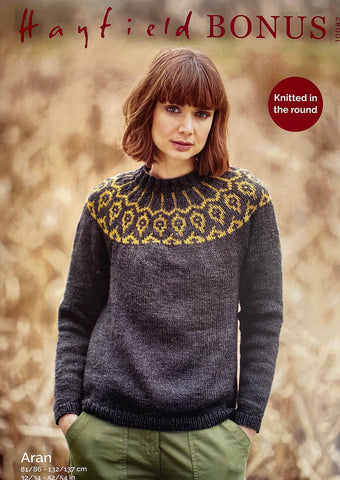 Image of cover of Sirdar knitting pattern 10082. An Aran sweater with a Fair Isle-style yoke. Knitted in dark grey with the yoke pattern in mustard