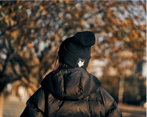 Woman wearing a puffy coat and Lone Wolf Fitness beanie as an athleisure outfit outside