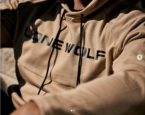 Tan athletic hoodie with Lone Wolf text across the front and two black strings hanging down from the hood