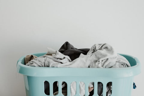 Dirty laundry in a teal basket 