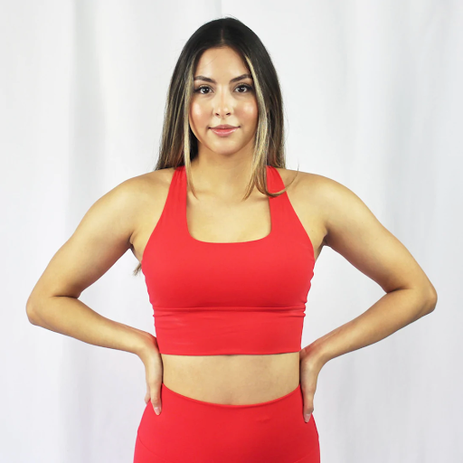 A woman wearing a matching red summer athleisure outfit with hands on her hips.