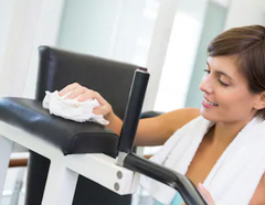 Woman Wiping Down Gym Equipment