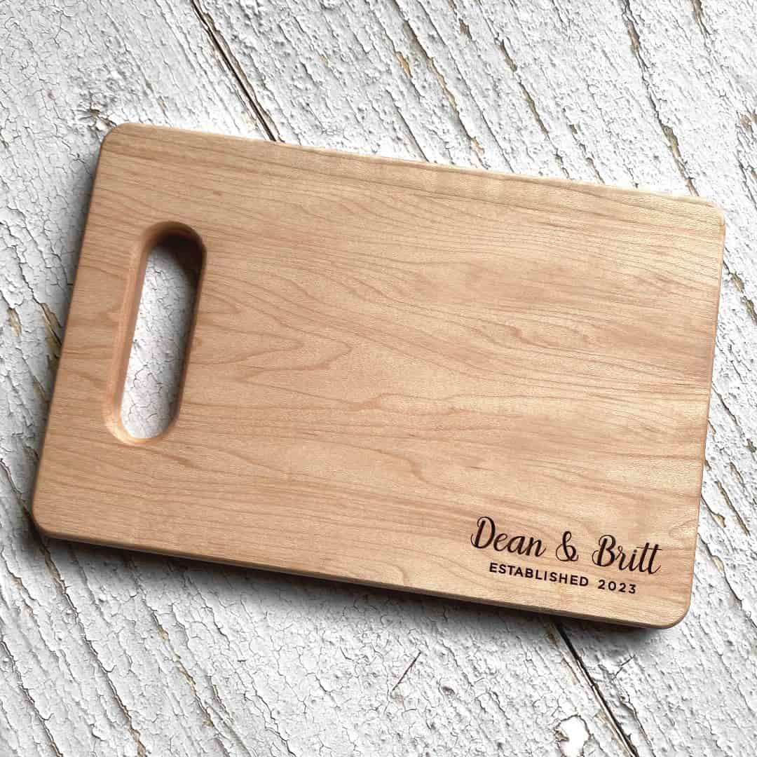 A wood cutting board with a name and date engraved on it