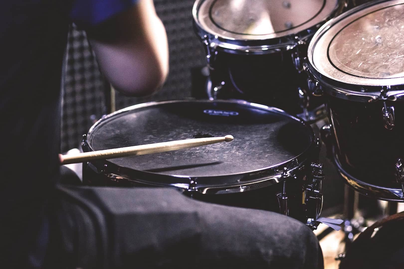 A man sitting at a drum set with a drumstick