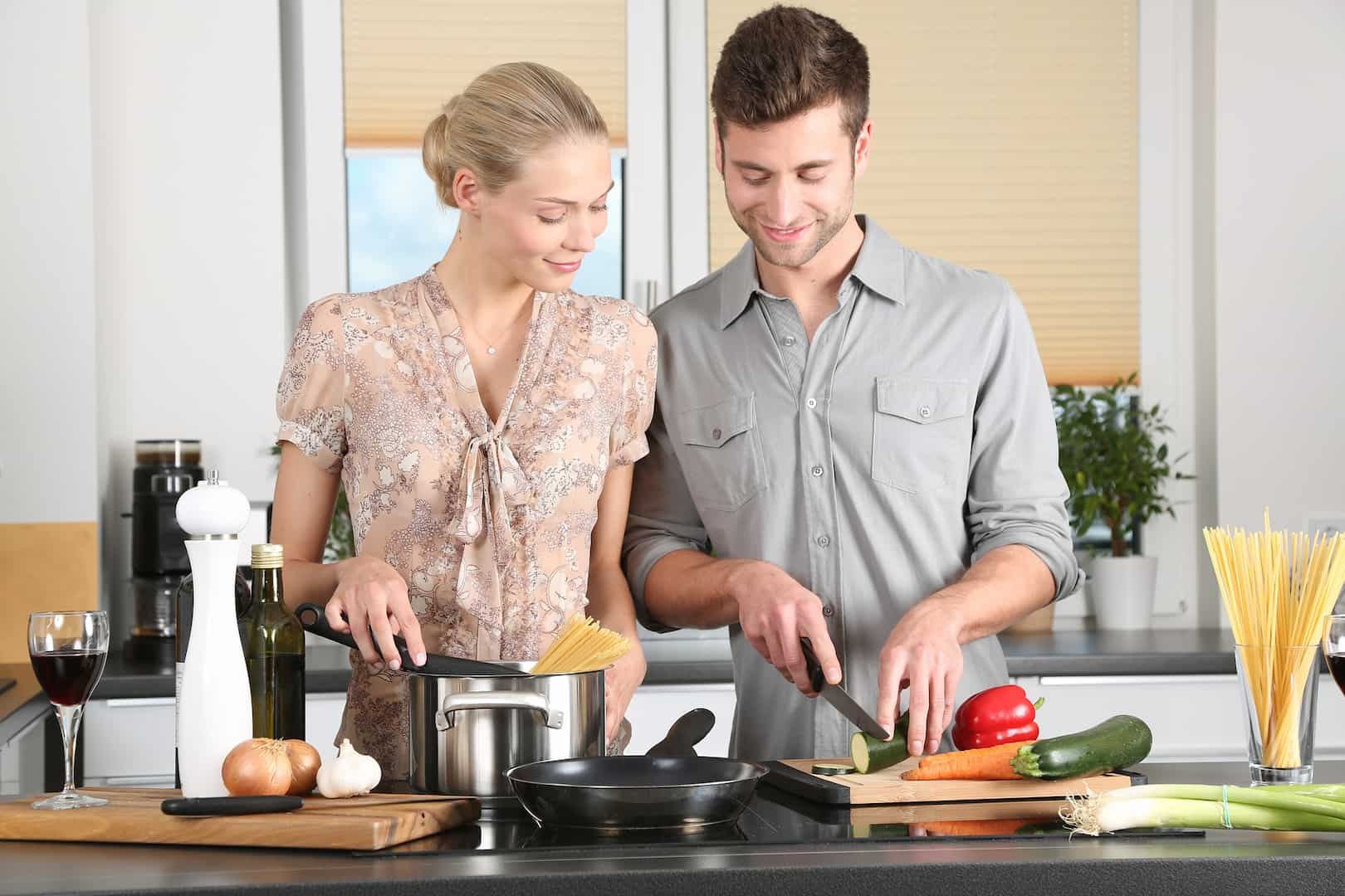 A man and woman cooking and using cutting boards