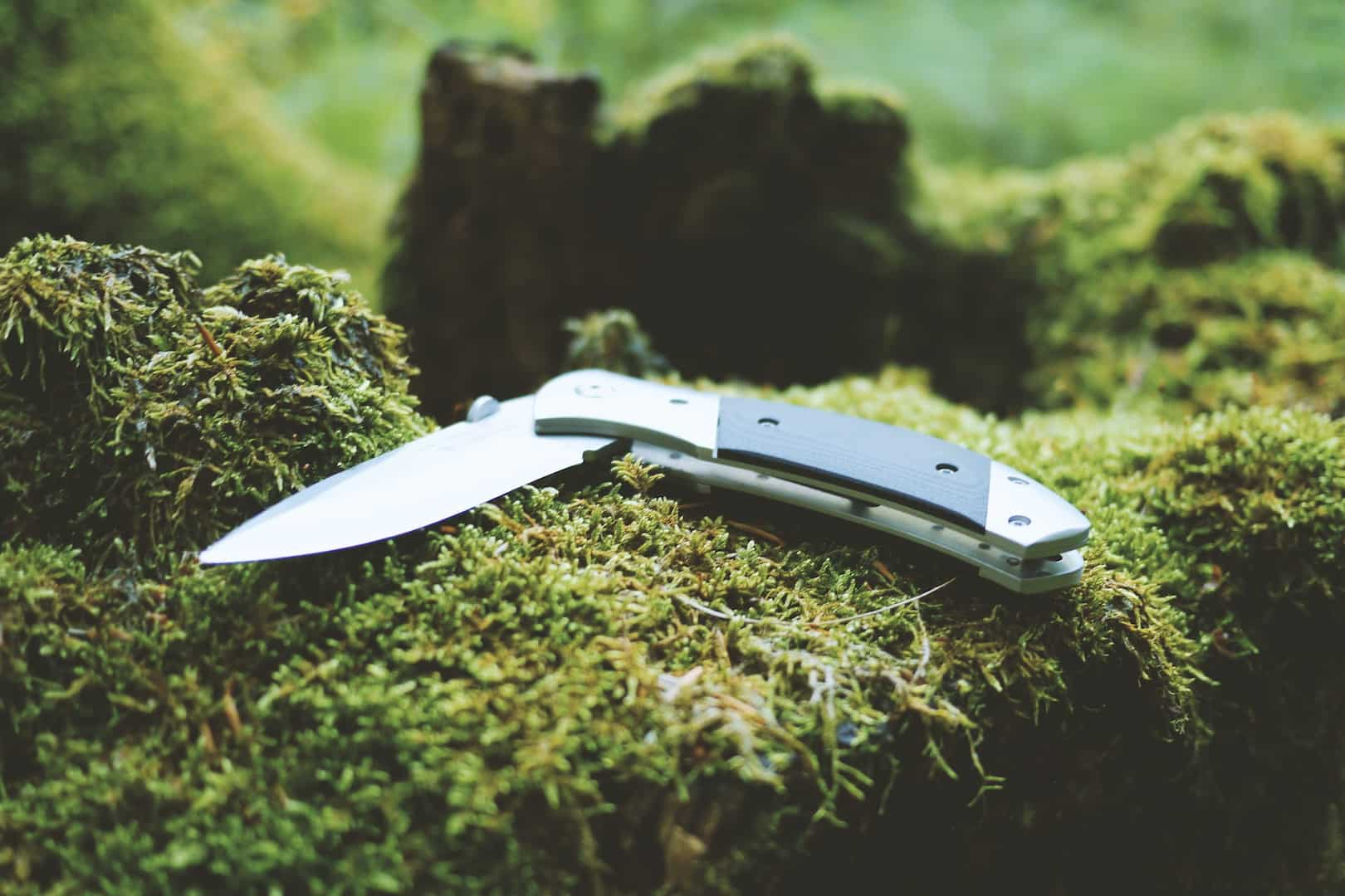 An open pocket knife on a log