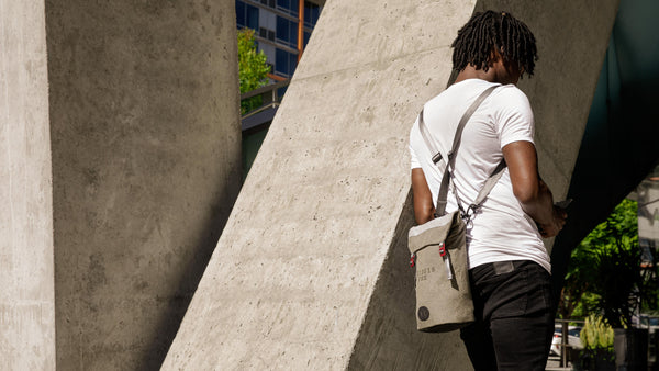 Man leans against wall with Fierce Hazel Backpack on his back