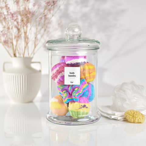 Large Glass Bath Bomb Storage Jar full of bright colourful bath bombs with white label saying bath bombs in black in a fresh white bathroom setting