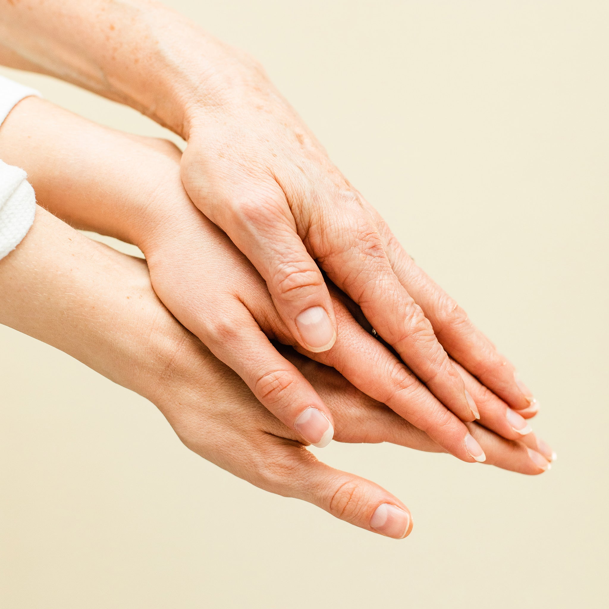 image of three hands of varying ages placed on top of each other. 