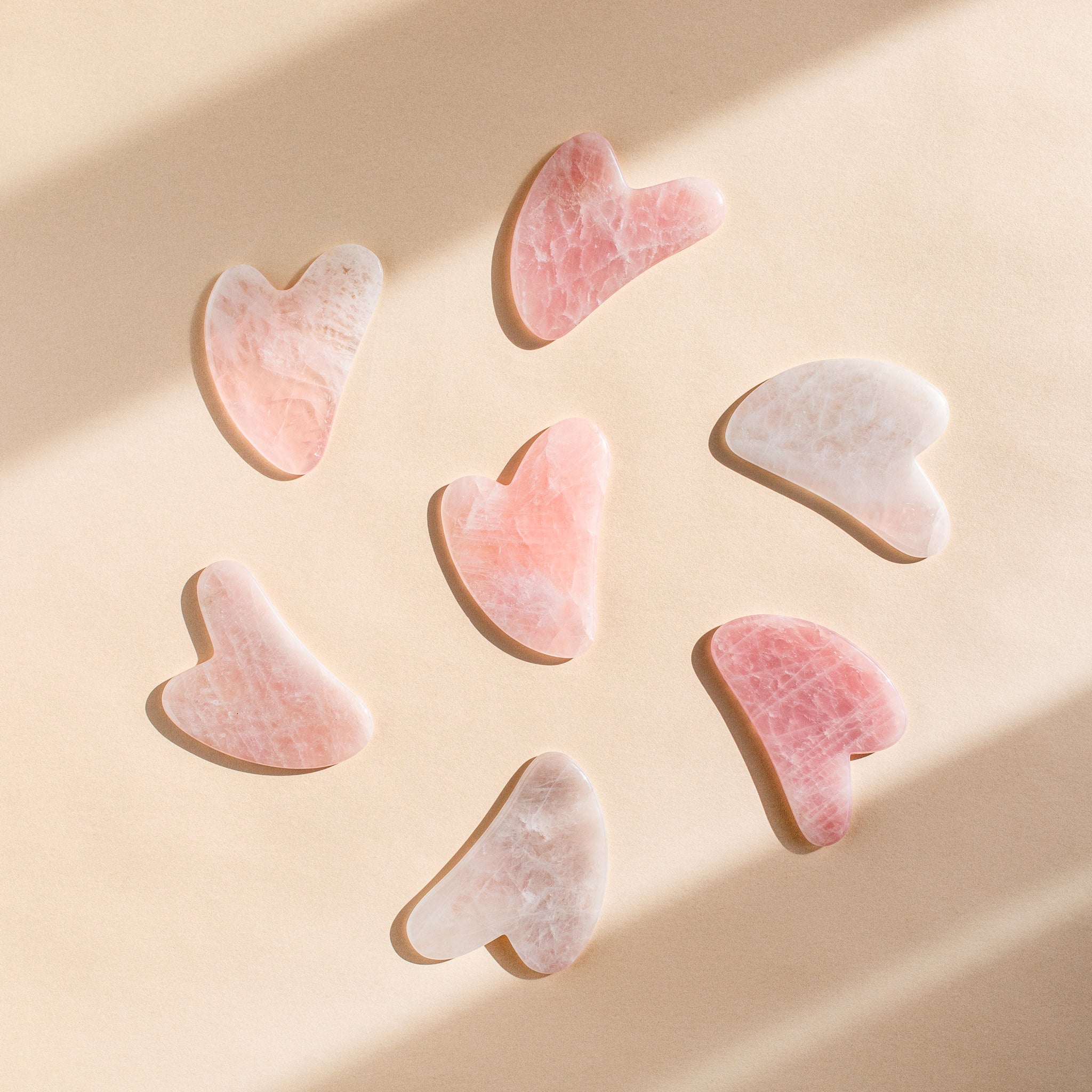 Image of rose quartz hand crafted gua sha tools in a circle. 