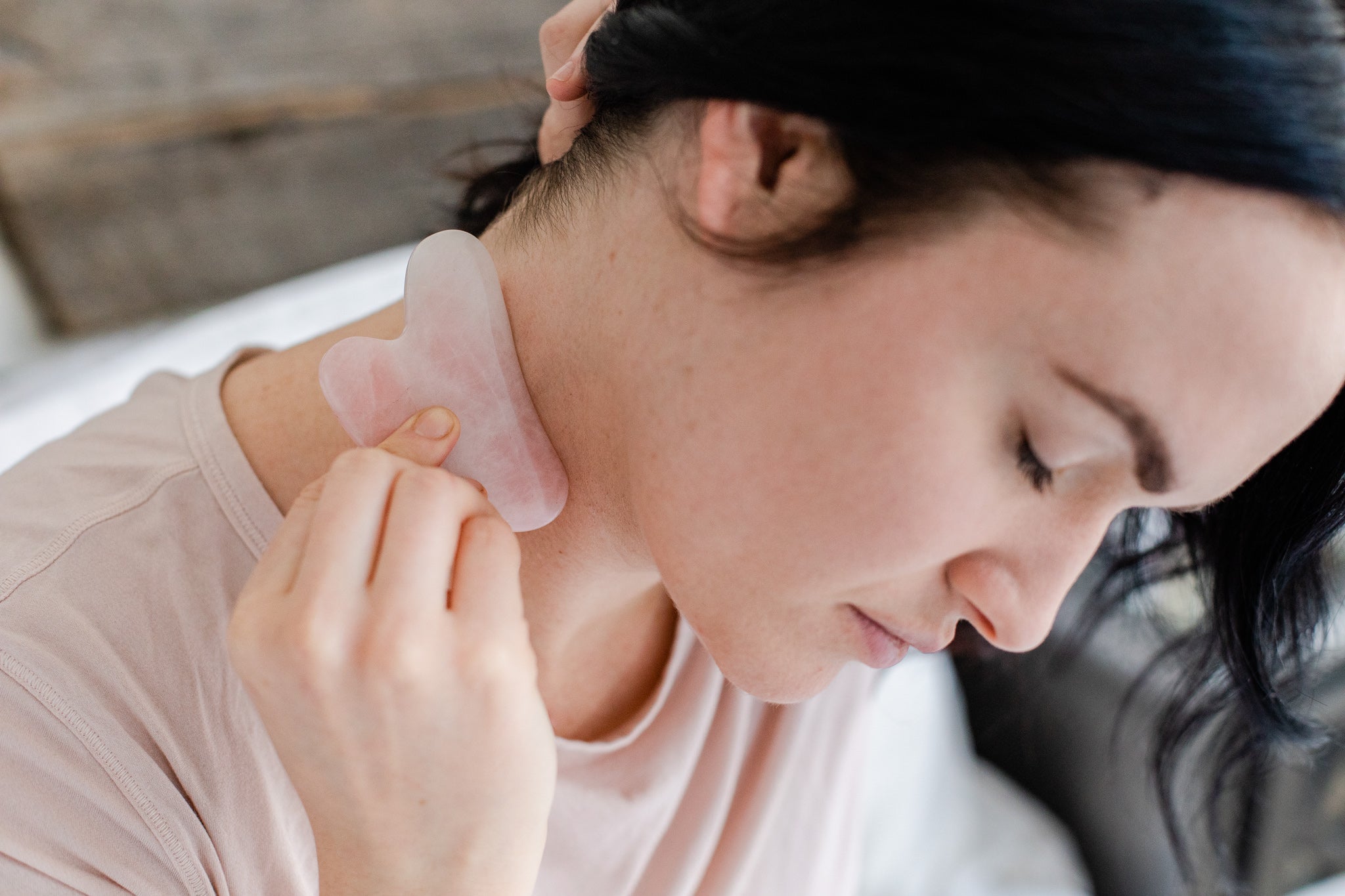 Image of woman using Gua Sha tool on her neck. 