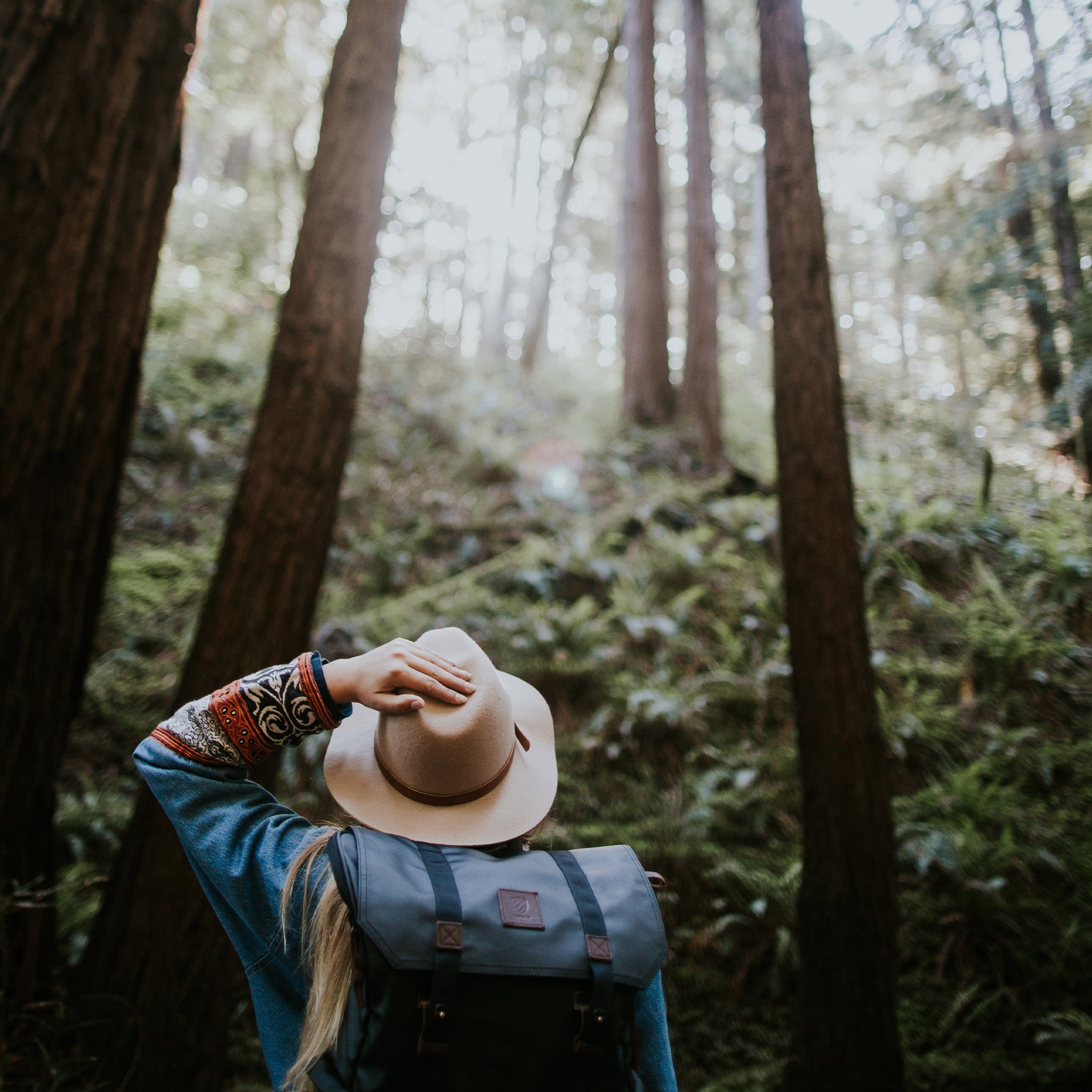 Woman hiking holding a hat. 