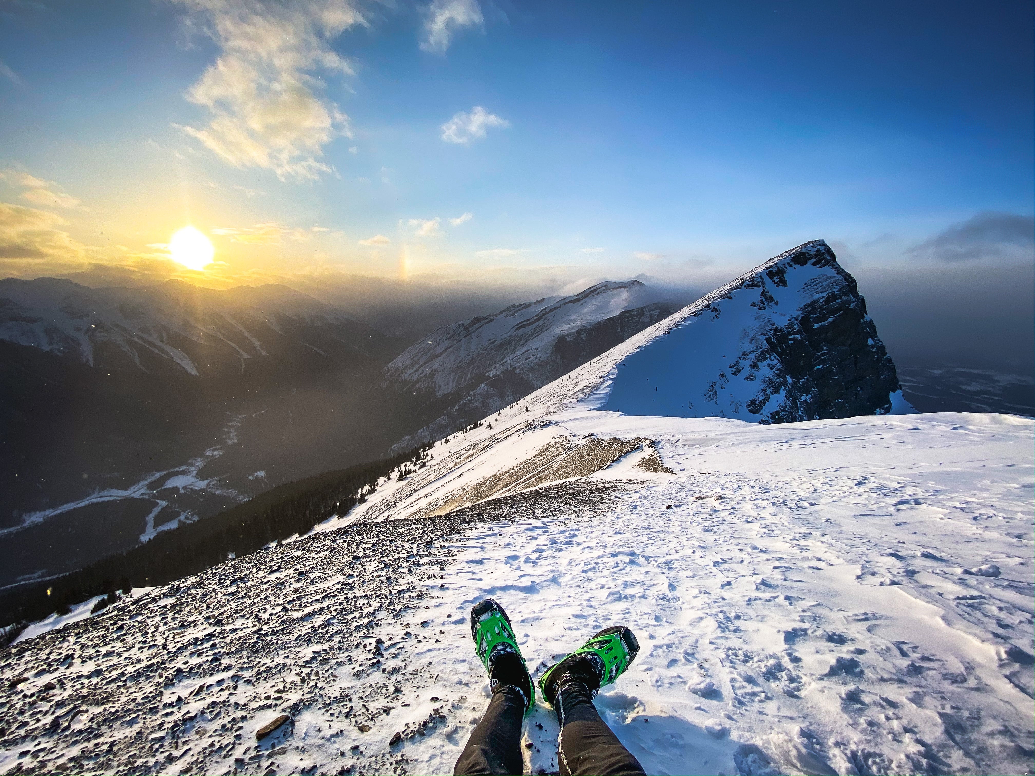 A pair of feet in running shoes wearing cleats for ice traction on a mountain top. 