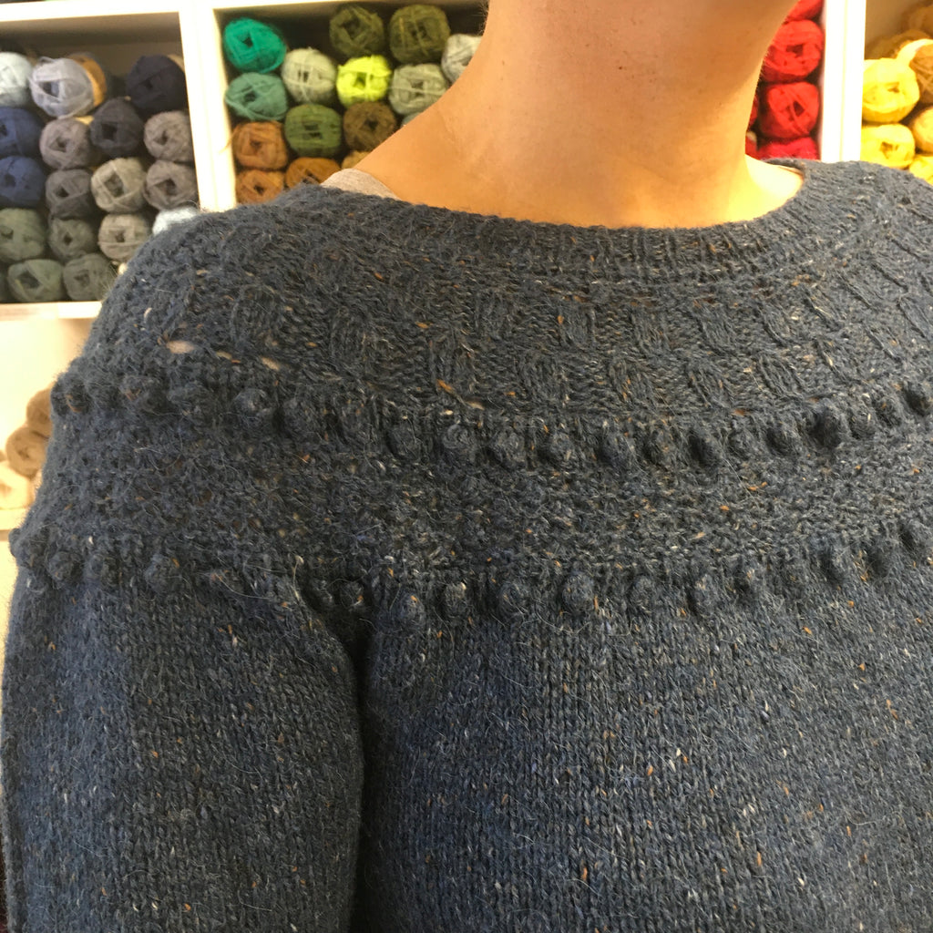 close up of dark blue handknit sweater lace and bobble yoke