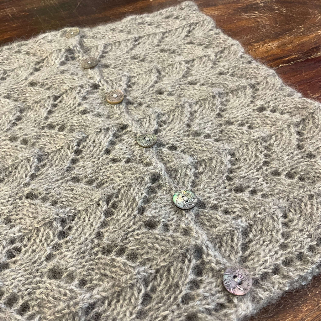 grey lace cowl with buttons on a dark wood table