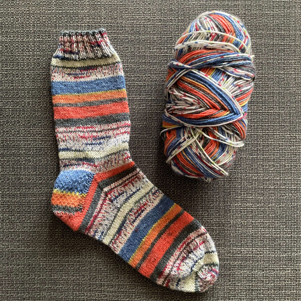 a hand knitted sock in blue and orange
