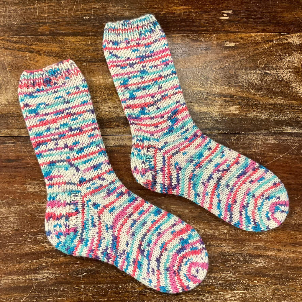 multicoloured thick hand knitted socks on a wooden table