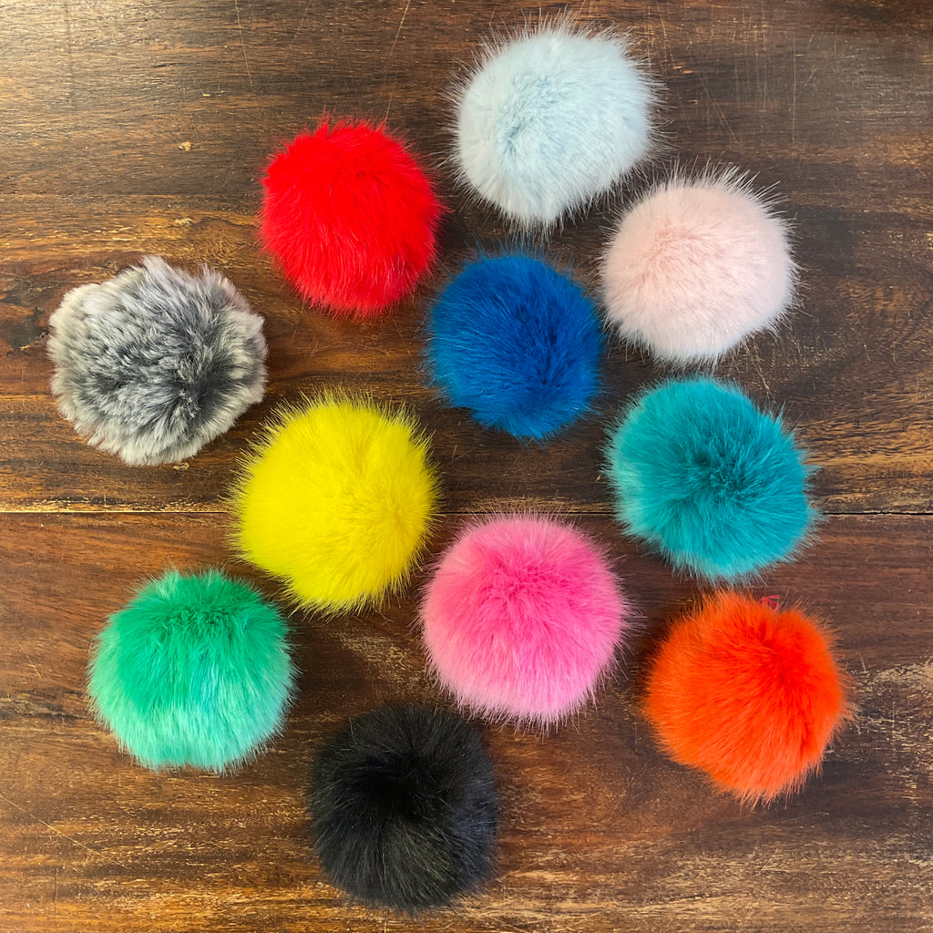 brightly coloured faux fur pom poms on a dark wood table