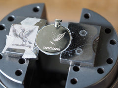 hand engraved bird crest on round pendant