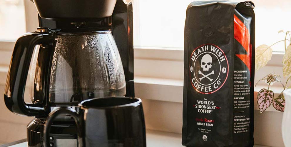 A black coffee maker with a black mug and a bag of Death Wish Coffee OG Dark Roast.