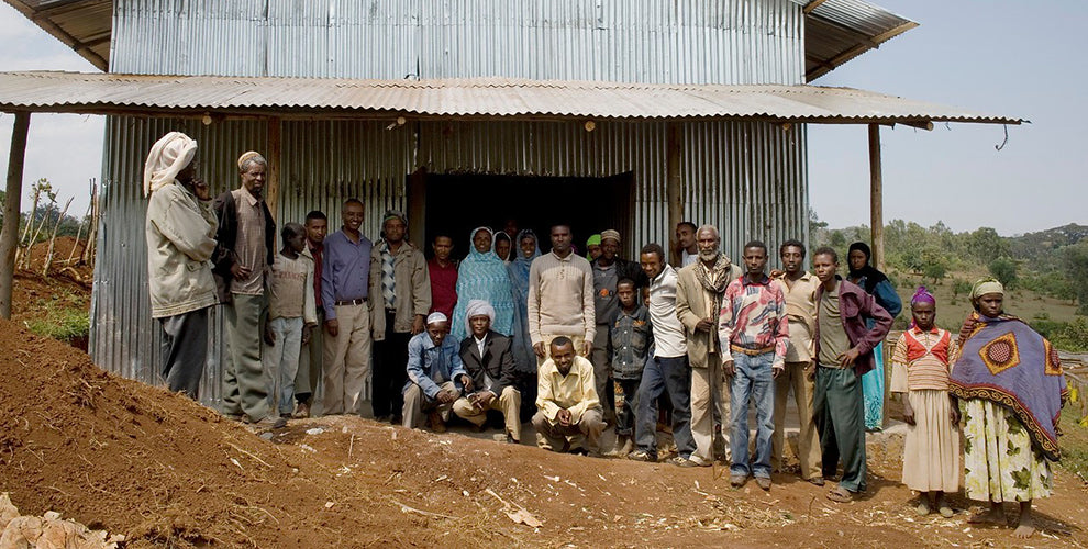 A group of Fair Trade coffee farmers standing in front of a large building.