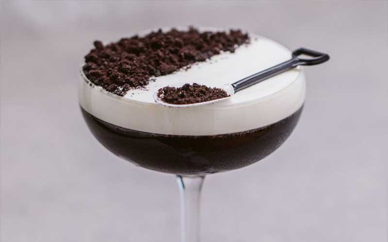 A dessert cocktail made with coffee and sprinkled oreos on top.