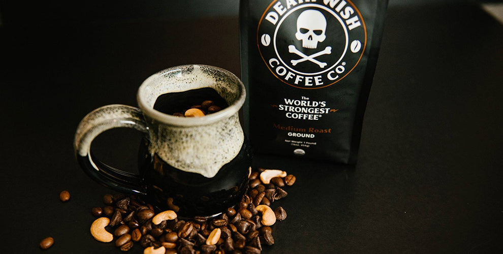 A bag of medium roast on a black table with a mug full of coffee beans and cashews.