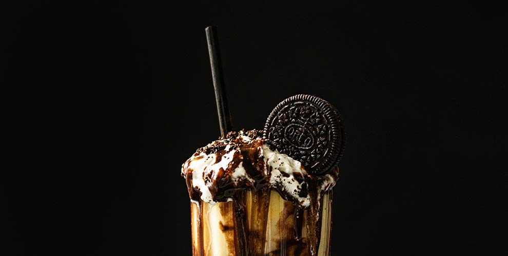 A coffee cocktail with chocolate syrup, whipped cream and an Oreo garnish.