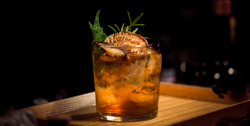 A rosemary vanilla cold brew coffee cocktail with a rosemary and orange garnish.