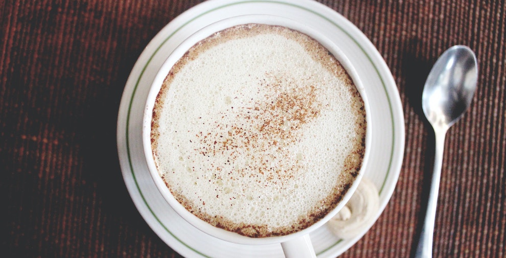 coffee in a white mug next to a spoon