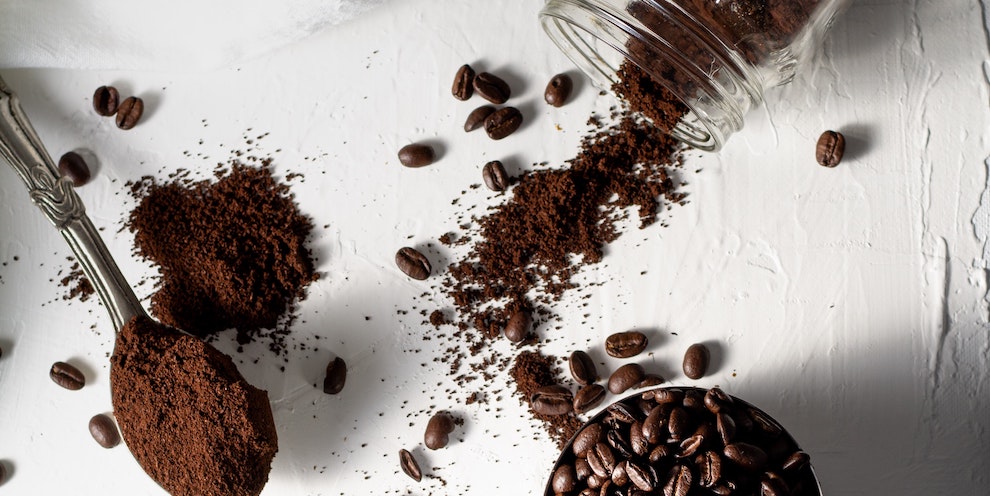 spoon full of coffee grounds and coffee beans