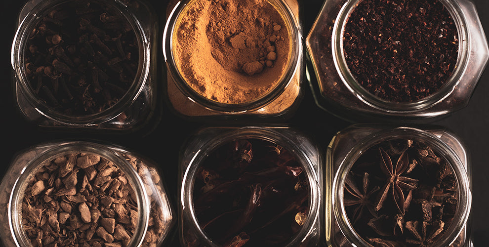 6 cooking spices that can be used in iced coffee all displayed in small glass jars.