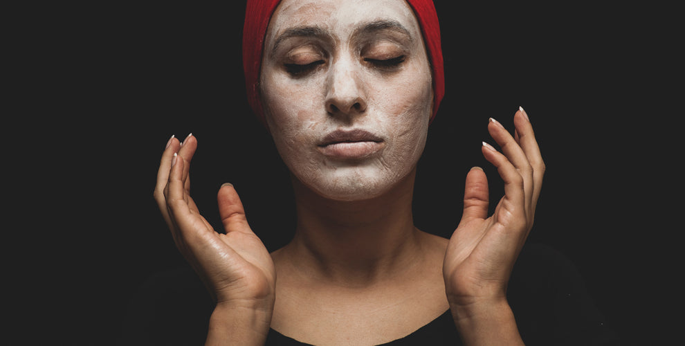 A woman applying a face mask for skin benefits.