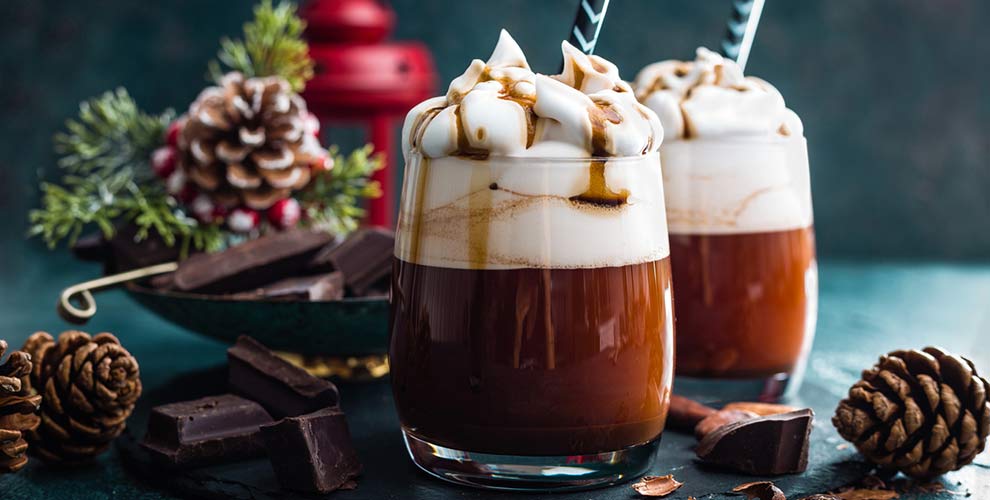 A festive christmas coffee cocktail featuring two wine glasses filled with coffee and whipcream on top.
