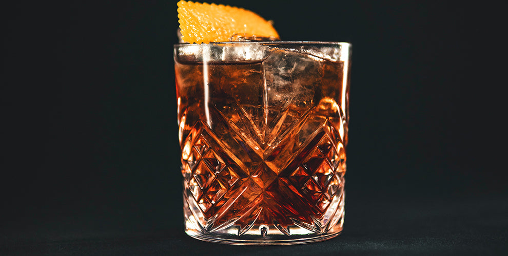 A cold brew negroni in a cocktail glass with an orange peel garnish.
