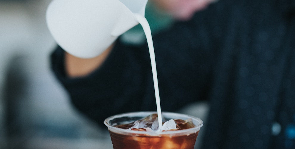 milk being poured into coffee cup