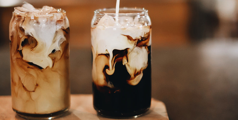 Two mason jars of cold brew coffee with ice and almond milk.