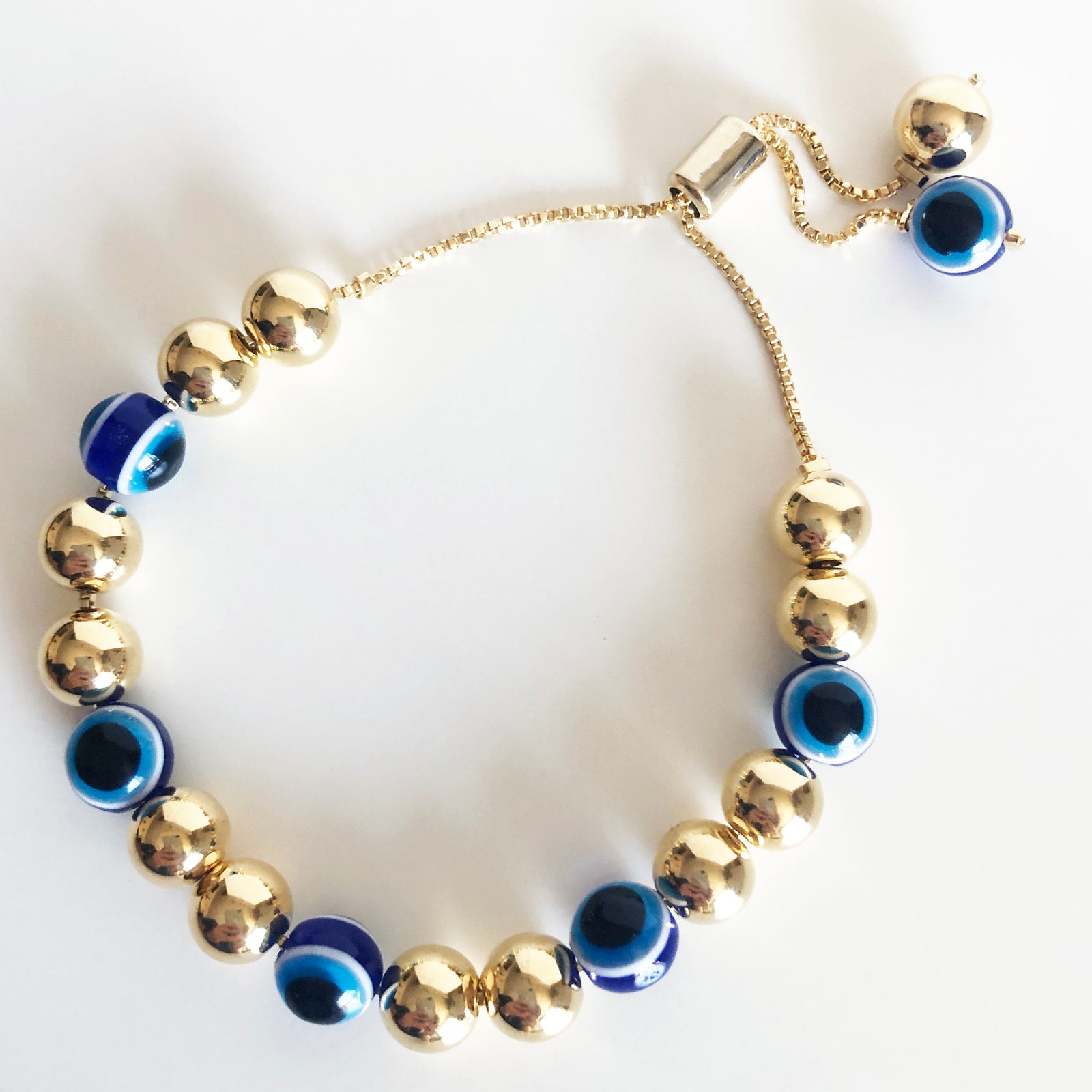 Alternating gold beads and evil eye beaded bracelet on a box chain with a bolo claps