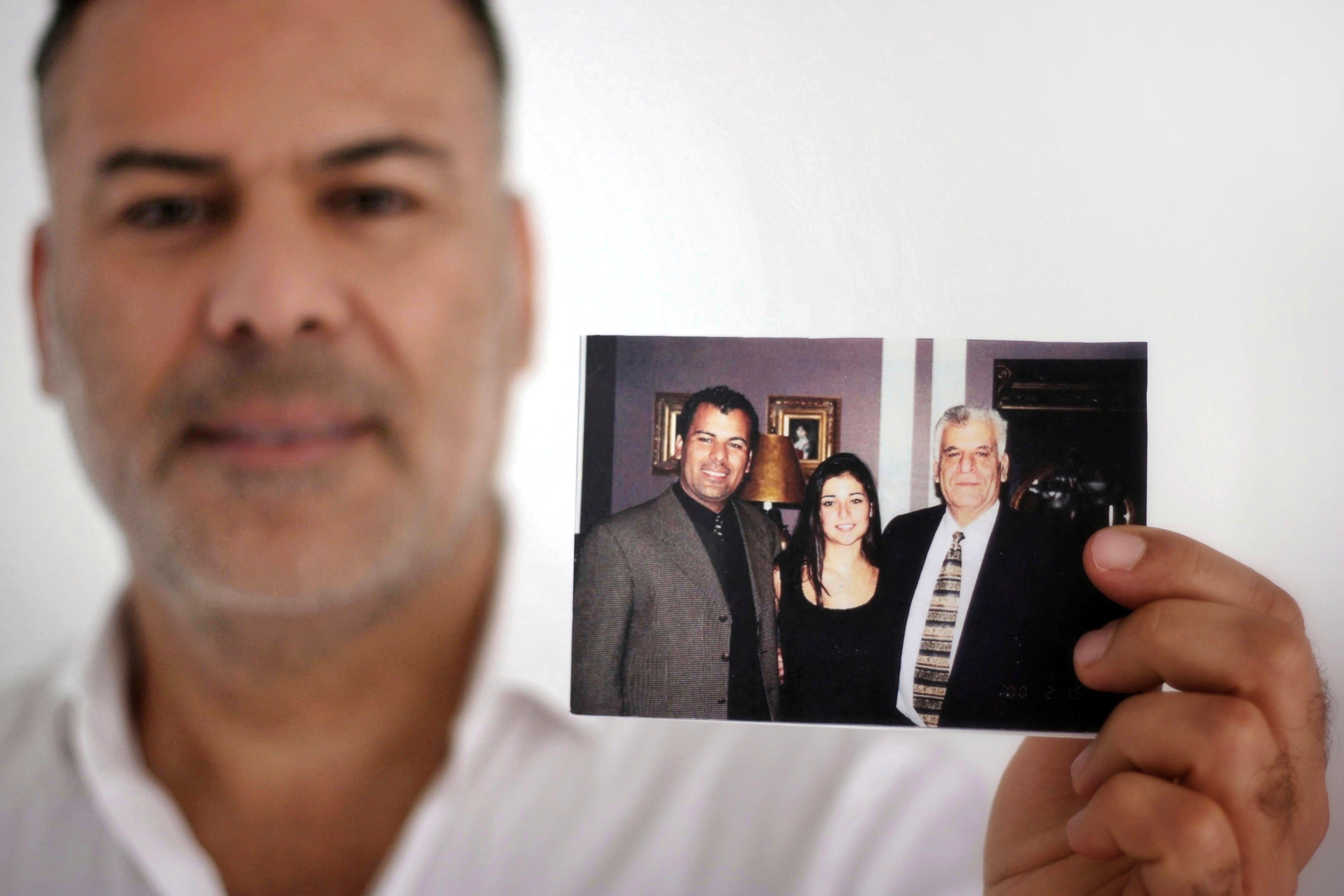 CEO Tony Chahine smiles and holds up a picture of his younger self standing with his father.