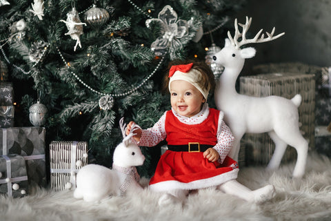 A baby girl sitting under the Christmas tree