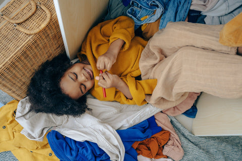 A kid playing in his wardrobe full of clothes