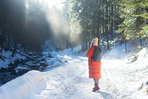 A woman in red jacket walk in the woods during winter