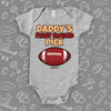 Cool baby onesie saying "Daddy's first round pick" and including the image of a football, color grey. 
