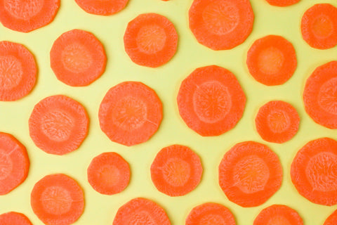 Fresh Carrot Slices on Yellow Background