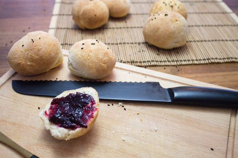 freshly baked bread with jam and bread knife on a wooden board