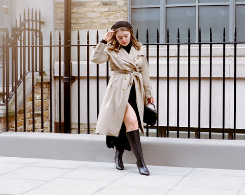 Knee high black boots paired with a beige trench coat